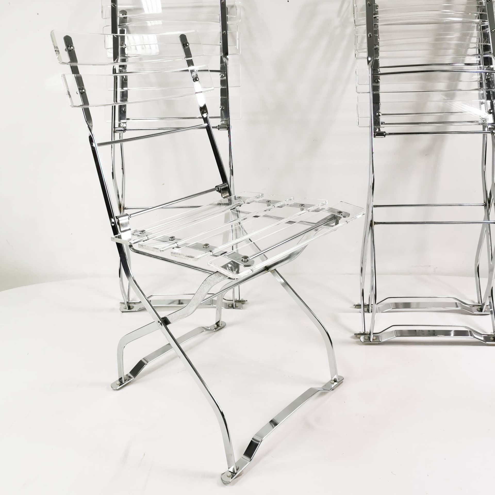 Set of four folding chairs, transparent plexiglass, silver metal, France, 1970s. - 347520